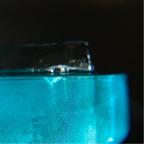 Détail d’un glaçon transparent dans un cocktail bleu